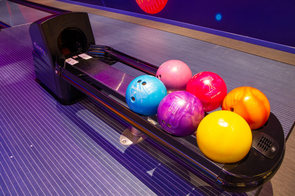 Bowling ball return unit loaded with house balls between two lanes