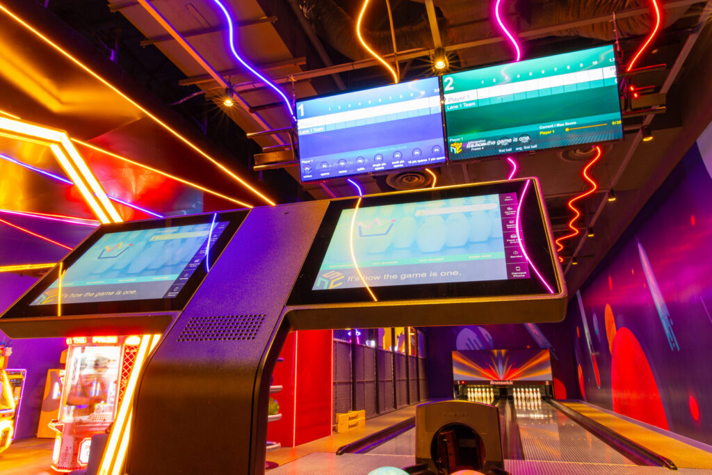 Overhead LCD scoring monitors and touchscreen lane consoles in a bowling centre